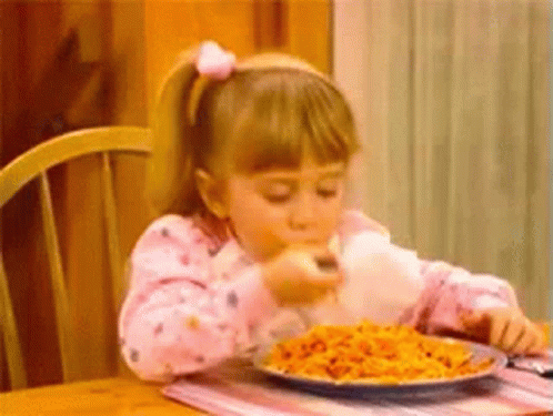 A girl shovelling spaghetti into her mouth