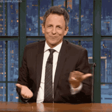 Seth Meyers moving his upturned palms in a 'weighing up' motion.