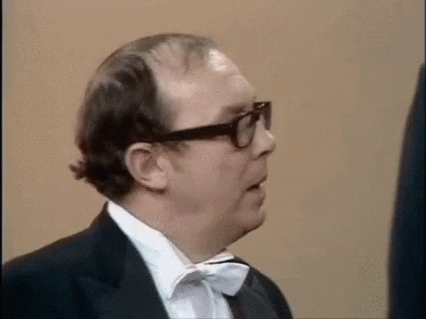Eric Morecambe pulling a face that suggests he thinks somethng is a bit awkward