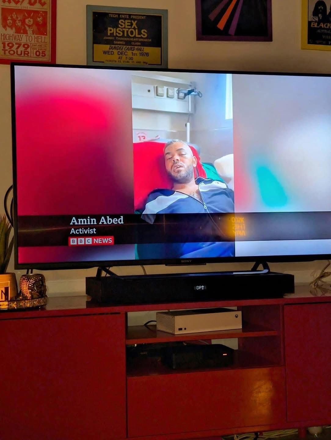 A man in a news item, lying in a bed. His name is Amin Abed