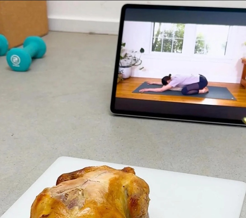 a roast chicken in front of an ipad showing someone doing a yoga pose that looks like a roast chicken