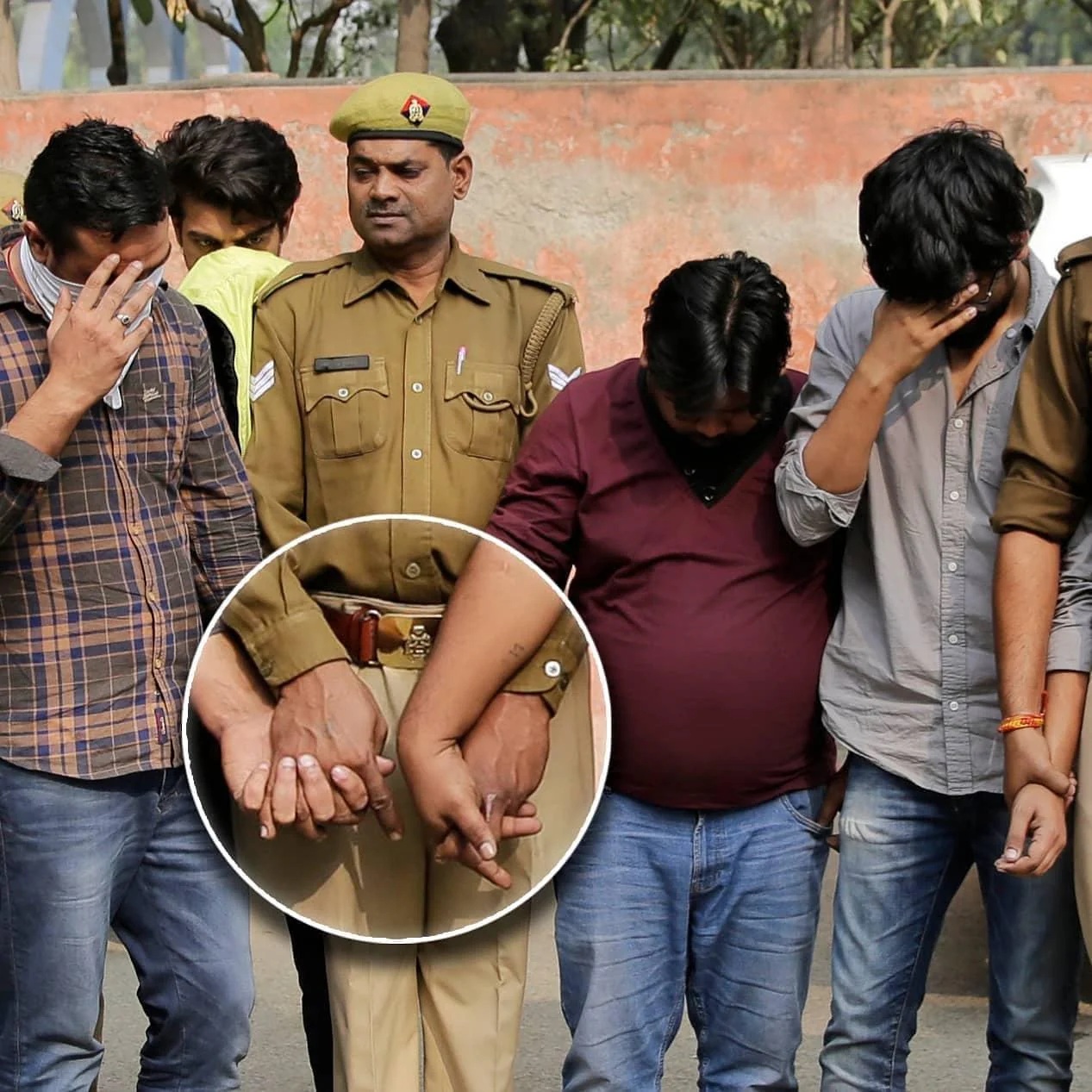 An Indian police officer in uniform, holding hands with a criminal on either side of him. They have their fingers entwined.