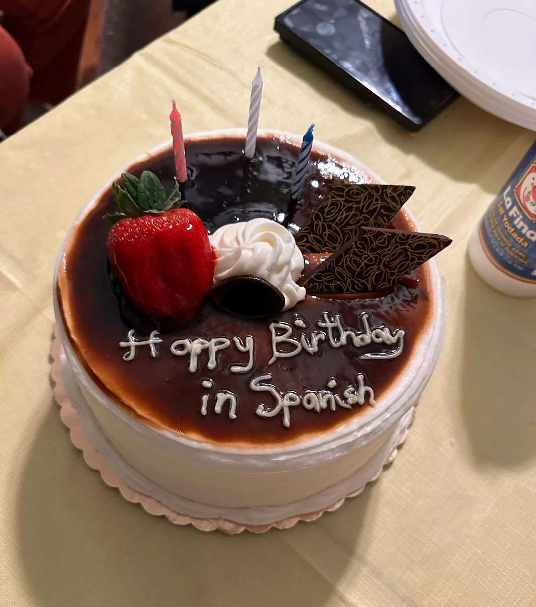A cake with "Happy birthday in Spanish" iced on it.