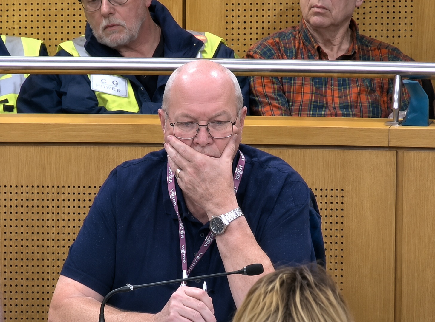 A concerned-looking elderly man with his hand over his mouth