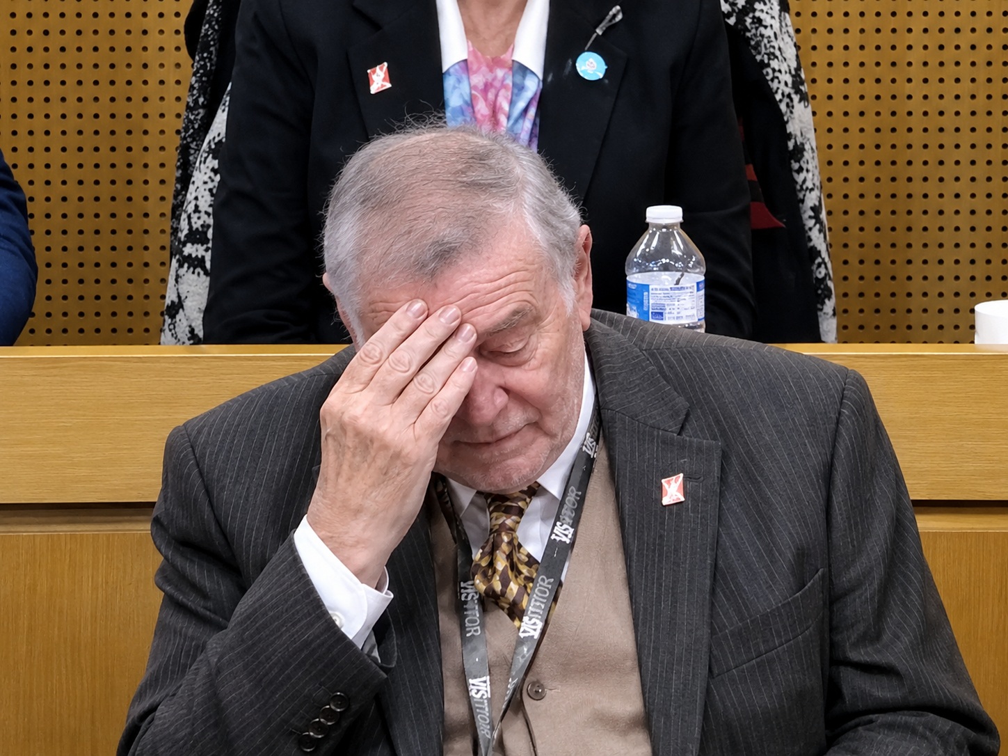 An elderly man with his head in his hands, looking either embarrassed or exasperated. 