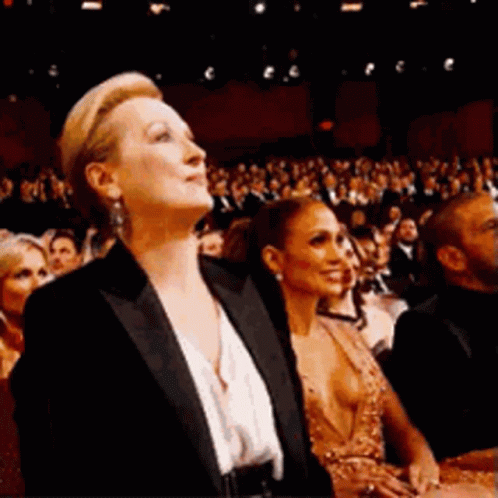 Meryl Streep pointing and smiling as part of a crowd giving Halle Berry a standing ovation for winning an Oscar