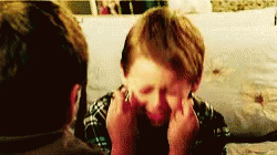 a young boy with his eyes tightly shut, crossing the fingers on both hands - wishing hard
